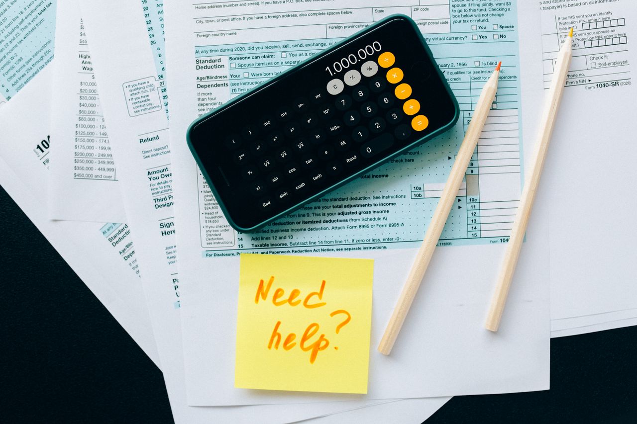 Mastering the First Impression: Your intriguing post title goes here Top view of financial papers with a calculator, pencils, and a note saying 'Need help?' indicating tax or accounting assistance.